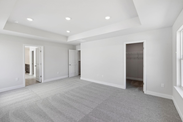 unfurnished bedroom with a tray ceiling, light carpet, baseboards, and recessed lighting