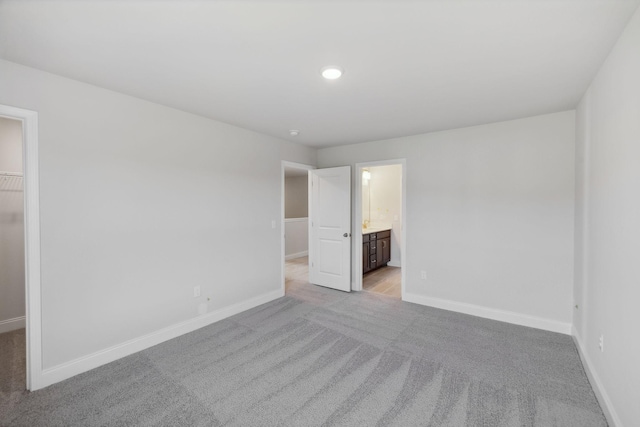 unfurnished bedroom with a spacious closet, baseboards, and light colored carpet