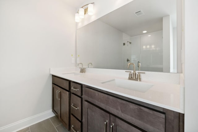 full bathroom with double vanity, a stall shower, visible vents, and a sink