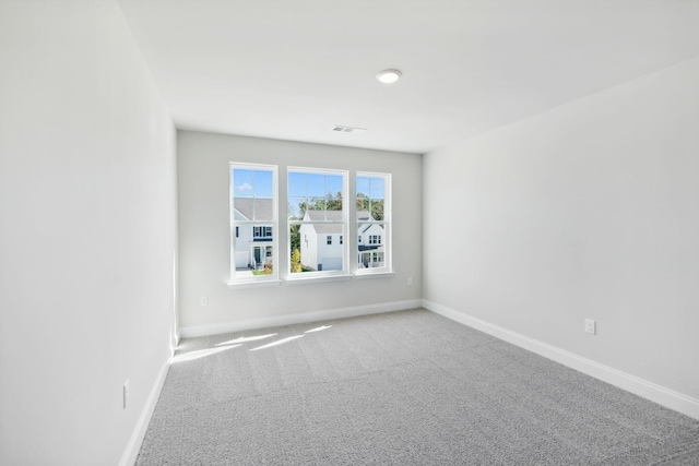 carpeted spare room with visible vents and baseboards