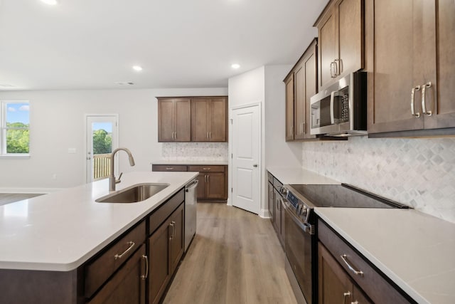 kitchen with stainless steel appliances, light countertops, a sink, and light wood finished floors