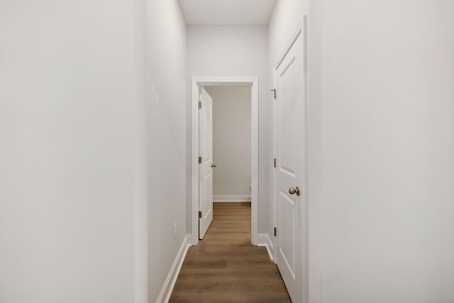 corridor featuring baseboards and wood finished floors