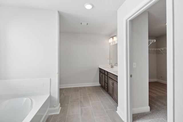 bathroom with a garden tub, a sink, visible vents, a spacious closet, and double vanity