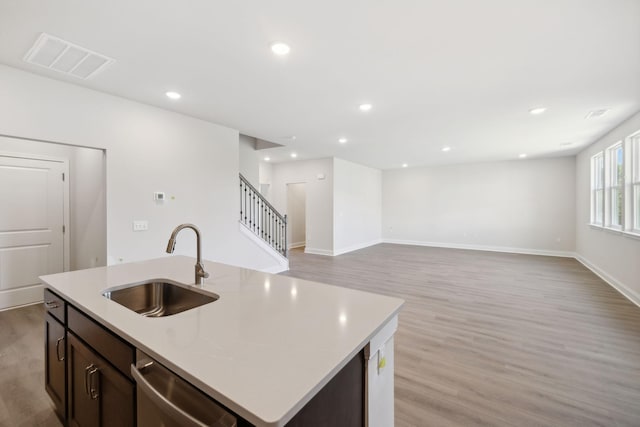 kitchen featuring stainless steel dishwasher, light wood-style flooring, visible vents, and a sink