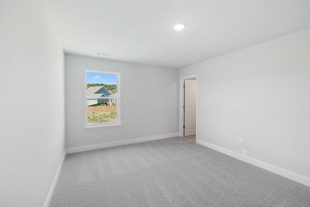 unfurnished room with carpet flooring, visible vents, and baseboards