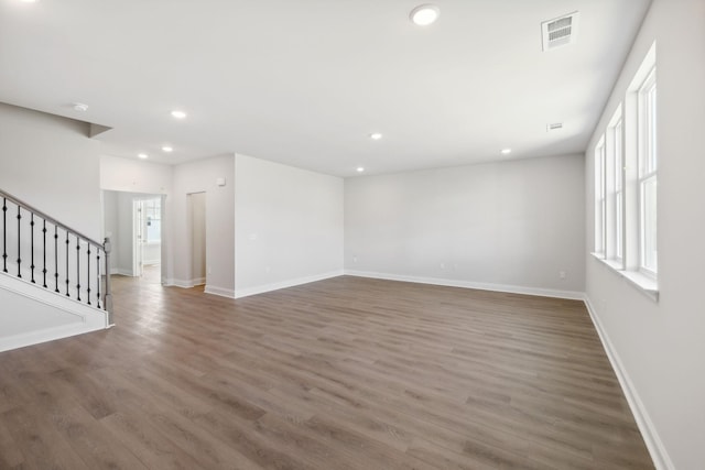 empty room featuring stairs, visible vents, wood finished floors, and recessed lighting