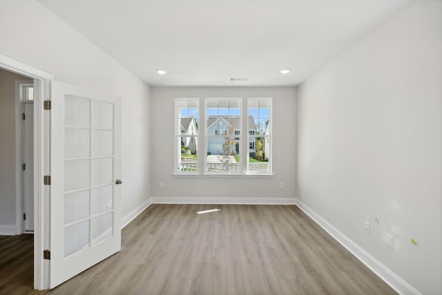 unfurnished room featuring recessed lighting, wood finished floors, visible vents, and baseboards