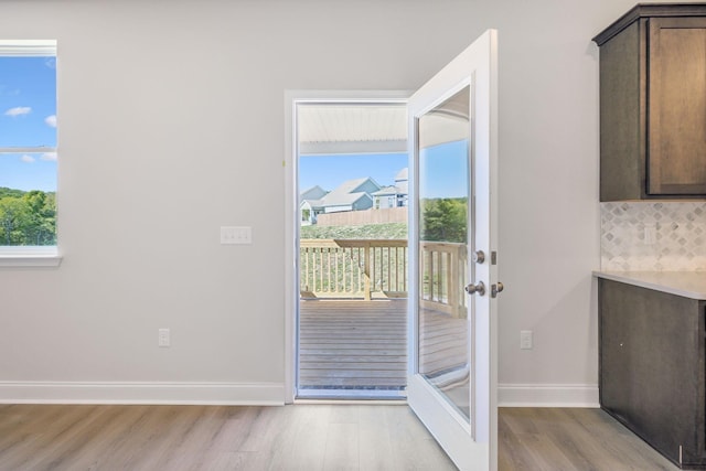 doorway with light wood-type flooring, plenty of natural light, and baseboards