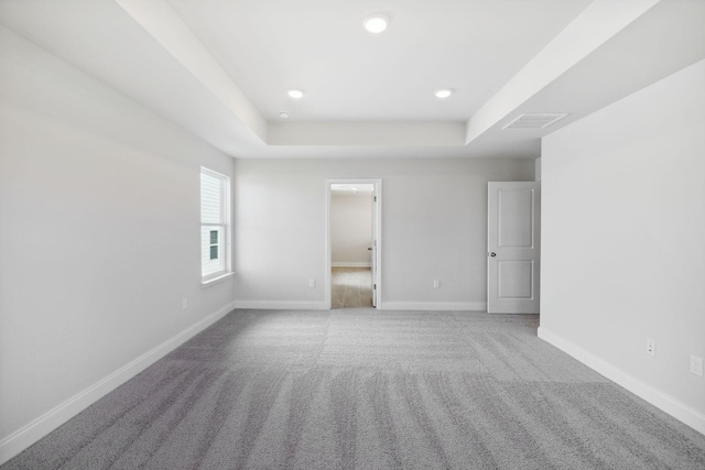 empty room with recessed lighting, carpet flooring, visible vents, baseboards, and a tray ceiling