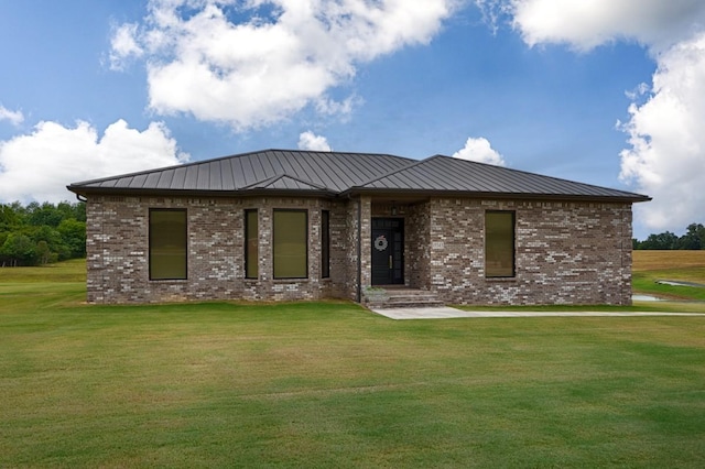 view of front of property with a front yard, a standing seam roof, brick siding, and metal roof