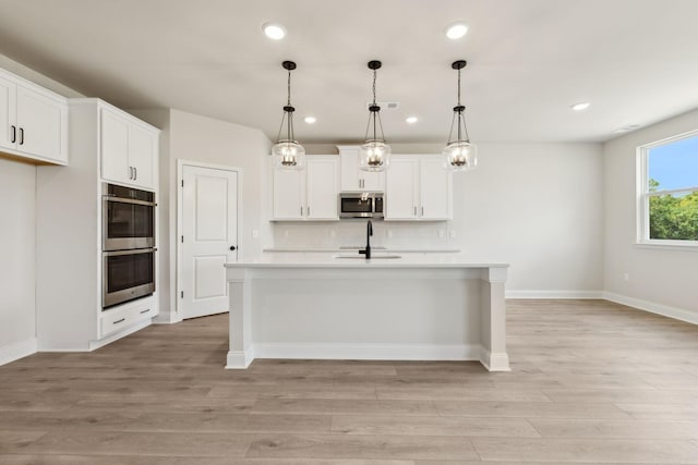 kitchen with appliances with stainless steel finishes, light countertops, backsplash, and white cabinetry