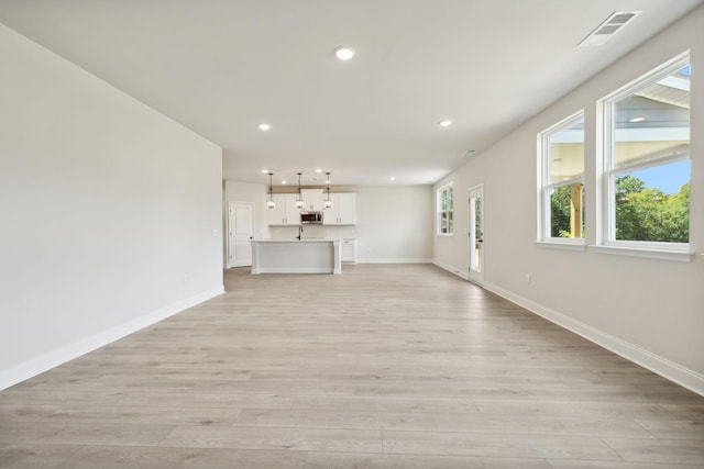 unfurnished living room with baseboards, light wood finished floors, visible vents, and recessed lighting