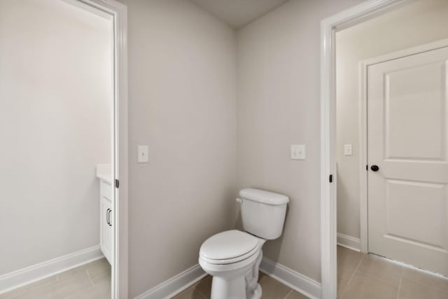 half bathroom with vanity, tile patterned flooring, toilet, and baseboards