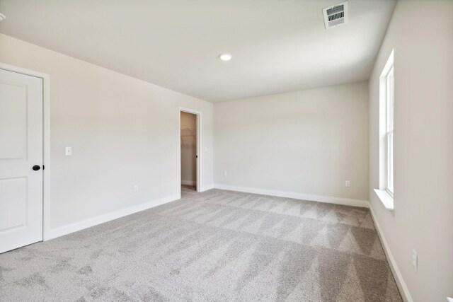 spare room featuring carpet, visible vents, and baseboards