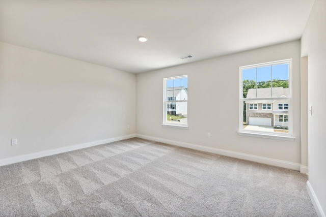 empty room featuring carpet, visible vents, and baseboards