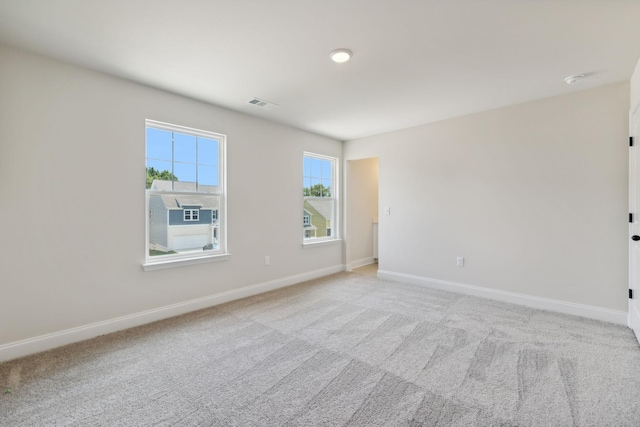 empty room featuring visible vents, light carpet, and baseboards