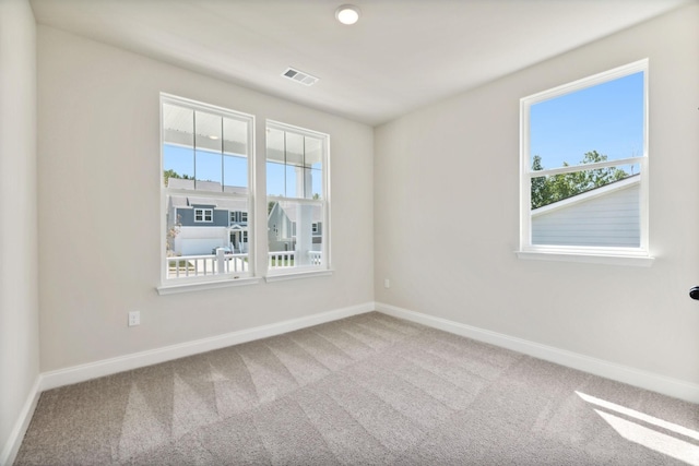 carpeted spare room featuring visible vents and baseboards