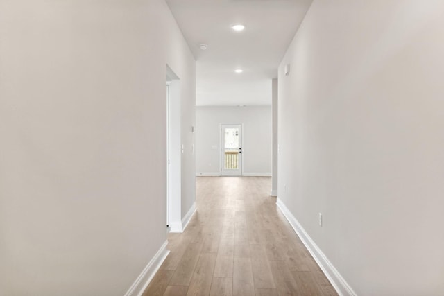 corridor with light wood finished floors, recessed lighting, and baseboards