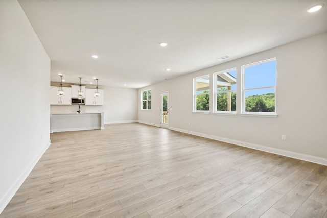 unfurnished living room with light wood-type flooring, recessed lighting, and baseboards