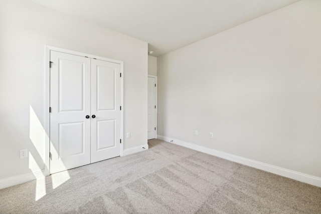 unfurnished bedroom featuring carpet, a closet, and baseboards