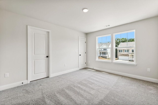 carpeted empty room featuring visible vents and baseboards