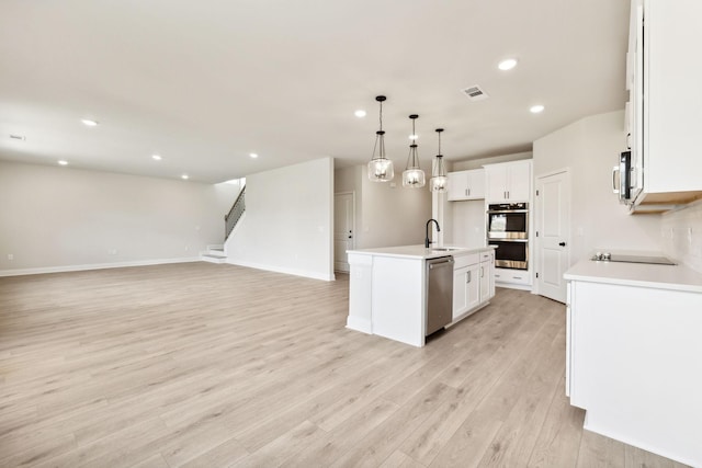 kitchen with visible vents, light wood-style floors, open floor plan, white cabinetry, and appliances with stainless steel finishes