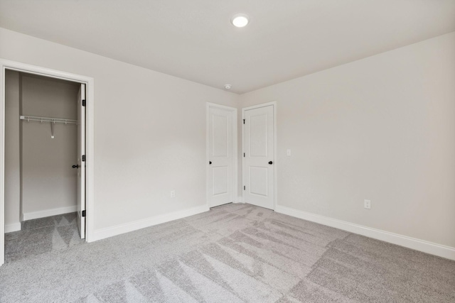 unfurnished bedroom with a spacious closet, baseboards, and carpet flooring