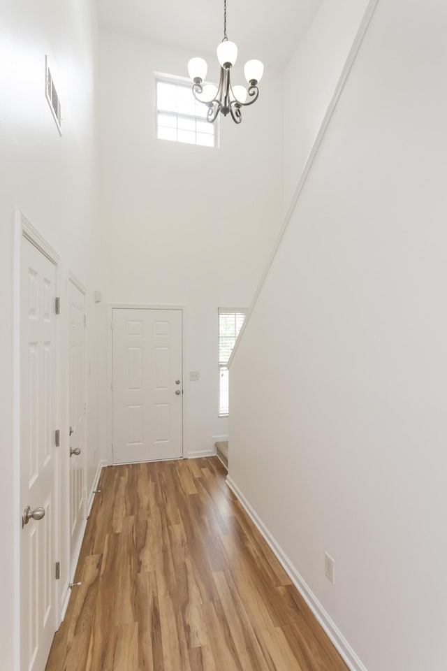 foyer entrance featuring a healthy amount of sunlight, light wood-style floors, a high ceiling, and visible vents