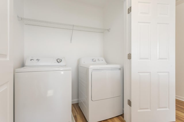 clothes washing area with laundry area, baseboards, light wood finished floors, and independent washer and dryer