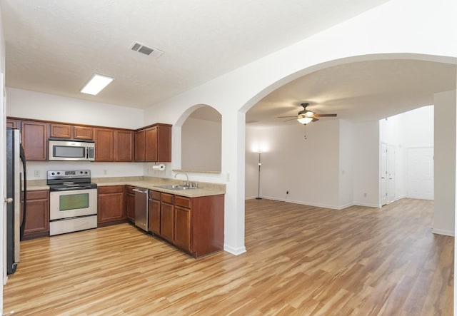 kitchen with open floor plan, appliances with stainless steel finishes, light wood-type flooring, and a sink