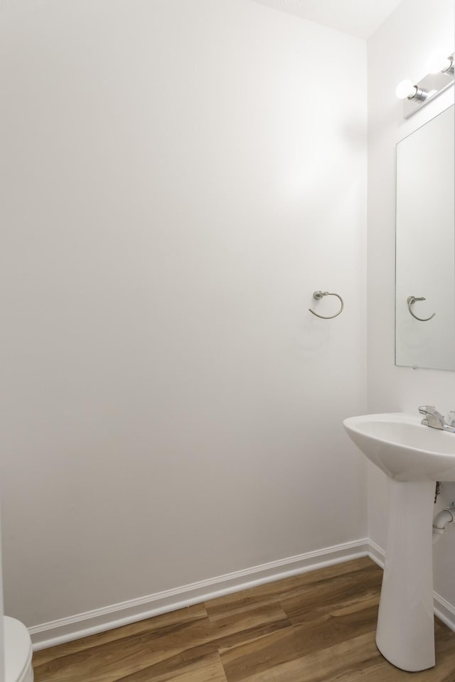 bathroom with a sink, wood finished floors, toilet, and baseboards