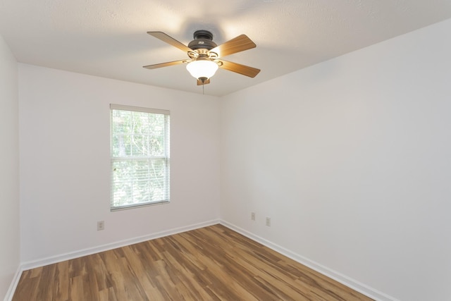 spare room featuring a ceiling fan, baseboards, and wood finished floors