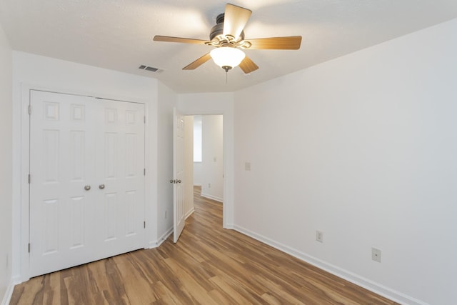 unfurnished room with a ceiling fan, light wood-type flooring, visible vents, and baseboards