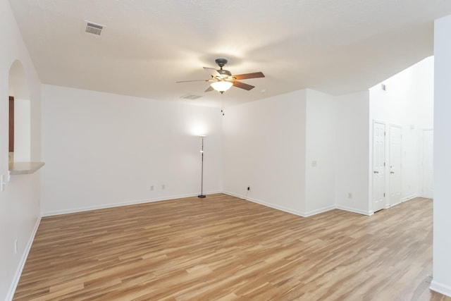 empty room featuring light wood-type flooring, visible vents, and a ceiling fan