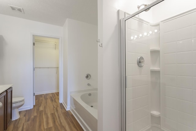 bathroom with wood finished floors, vanity, visible vents, walk in shower, and a bathtub