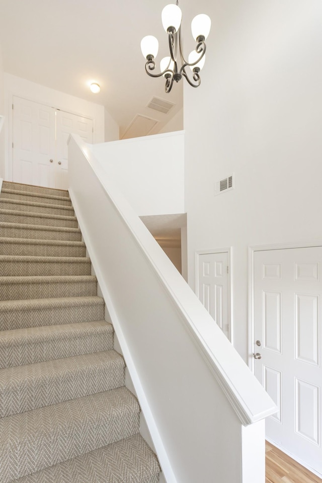 staircase featuring visible vents and an inviting chandelier