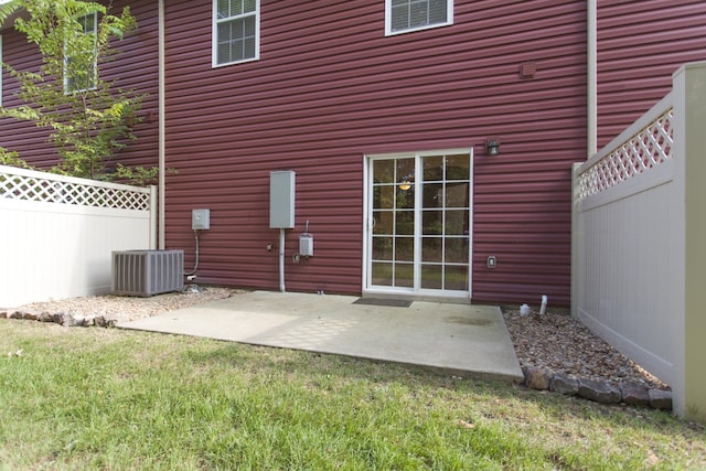 back of property with central air condition unit, fence, a lawn, and a patio