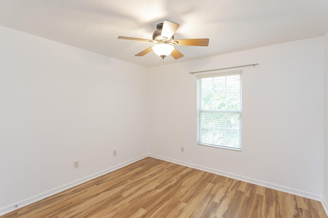 empty room featuring light wood-style floors, baseboards, and a ceiling fan