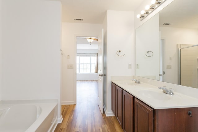 full bathroom with visible vents, wood finished floors, a sink, and a bath