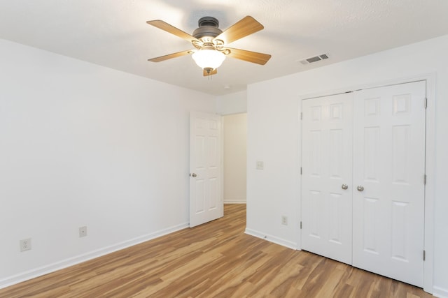 unfurnished bedroom featuring baseboards, visible vents, ceiling fan, light wood-type flooring, and a closet