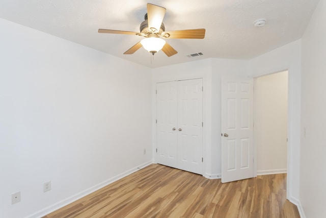 unfurnished bedroom featuring baseboards, a closet, visible vents, and light wood-style floors