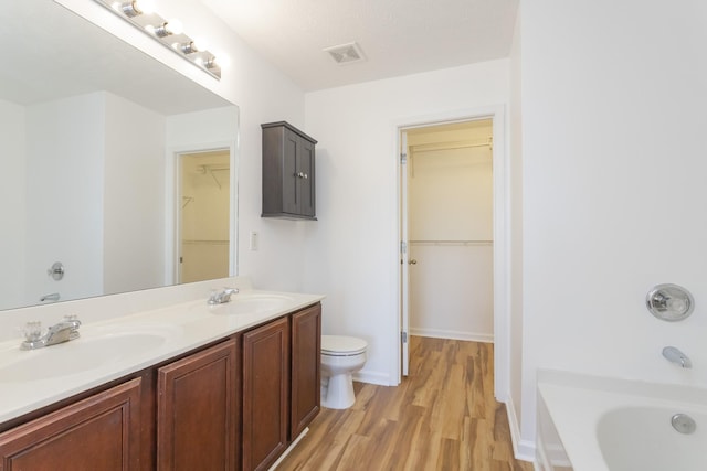 bathroom featuring toilet, a bathing tub, a sink, and visible vents