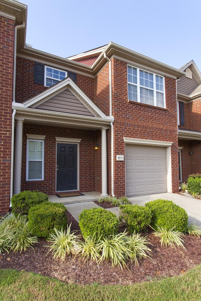 townhome / multi-family property featuring a garage, concrete driveway, and brick siding