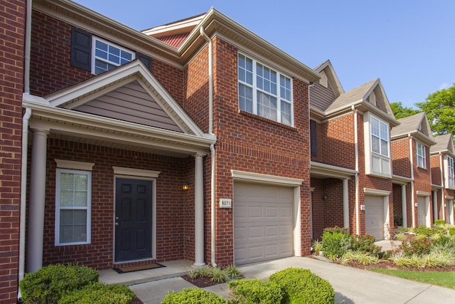 multi unit property featuring a garage, brick siding, and driveway