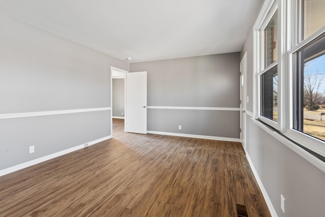 empty room featuring baseboards, visible vents, and wood finished floors