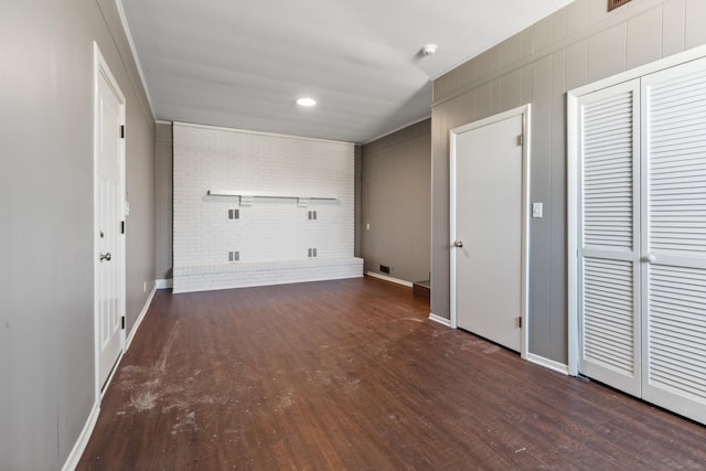 laundry room featuring baseboards, visible vents, brick wall, and wood finished floors