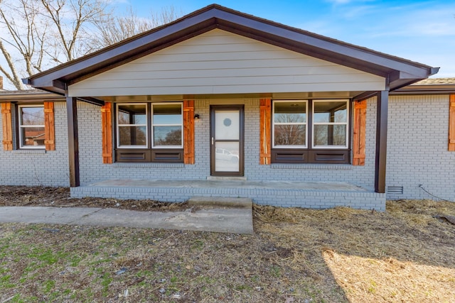 bungalow-style home with covered porch and brick siding