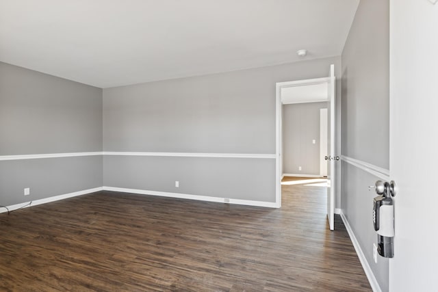 empty room featuring dark wood-style flooring and baseboards