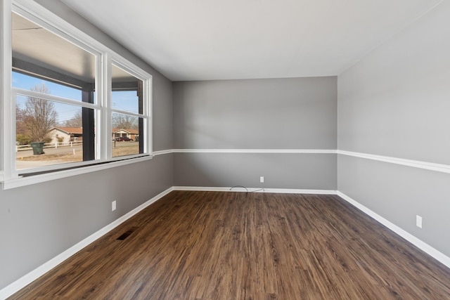 empty room with dark wood-style floors, baseboards, and visible vents