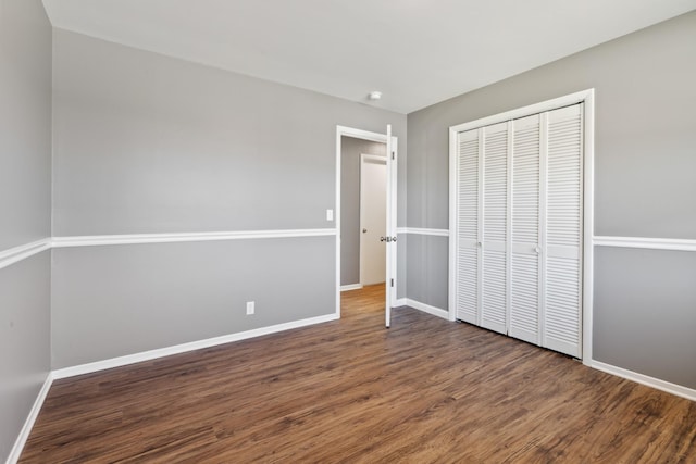 unfurnished bedroom featuring a closet, baseboards, and wood finished floors